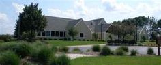 a large house sitting in the middle of a lush green field with lots of trees