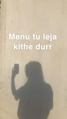 the shadow of a person holding a camera in front of a wall that says menu tu jeja kithe dur