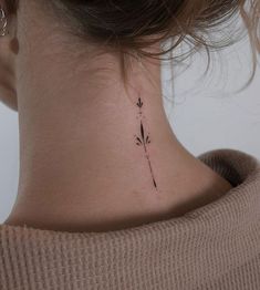 a woman's neck with a small flower tattoo on the back of her neck