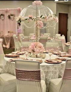 a table set up with white chairs and pink flowers