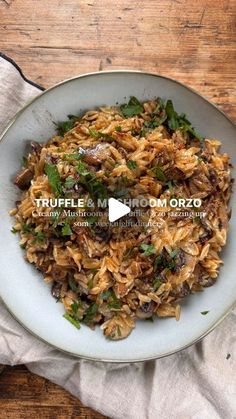 a white plate filled with rice and mushrooms on top of a wooden table next to a napkin