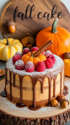 a cake sitting on top of a wooden plate covered in frosting and berries next to pumpkins