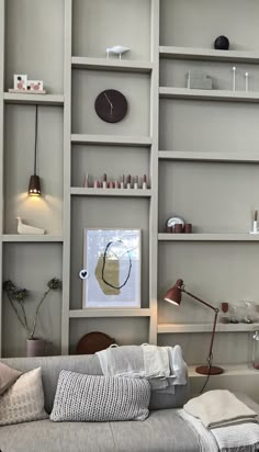 a living room filled with lots of furniture next to a wall mounted book shelf covered in shelves