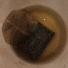 a white bowl filled with brown liquid next to a black object on top of a table