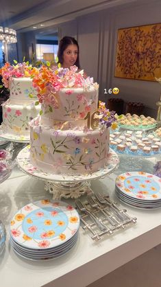 a woman standing in front of a table filled with cakes and cupcakes on plates