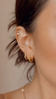 a close up of a person with ear piercings on their ears and wearing gold jewelry