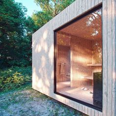 an outdoor sauna in the middle of a wooded area with trees and grass around it