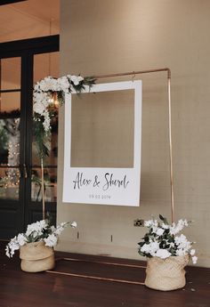 two vases with flowers are sitting on a table in front of a photo frame