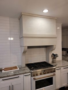 a stove top oven sitting inside of a kitchen next to white cabinets and counter tops