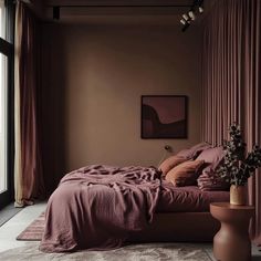 a bedroom with a large bed covered in pink sheets and pillows next to a window