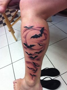 a person with a tattoo on their leg that has bats flying out of the sky