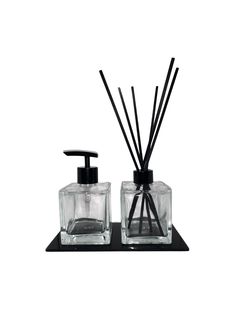 two square glass containers with black reeds and soap dispenser on top