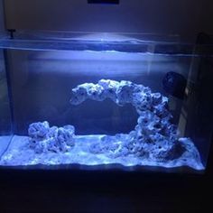 an aquarium filled with water and rocks in the middle of a dark room next to a wall