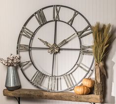 a large metal clock sitting on top of a shelf next to a vase with flowers