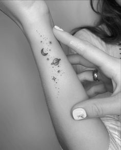 a woman's arm with stars and planets tattooed on the left side of her arm