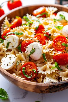 a wooden bowl filled with pasta and tomatoes