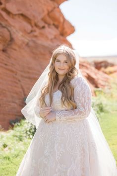 a woman in a wedding dress poses for a photo with her veil blowing in the wind