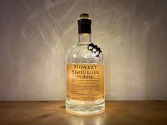 a bottle of monkeyy liquor sitting on top of a wooden table next to a wall