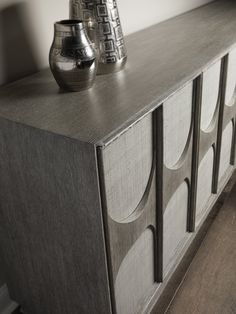 a silver vase sitting on top of a wooden dresser