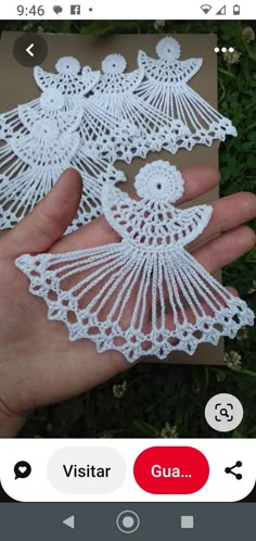 two white crocheted angel ornaments are held in the palm of someone's hand