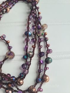 three stranded necklaces with purple and green beads