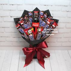 a bouquet of chocolates and candy bars wrapped in red ribbon on a white brick wall