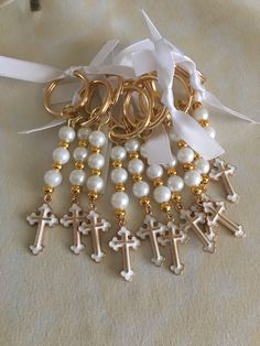 a bunch of gold and white beads with cross charms on it's sides, tied together by a ribbon