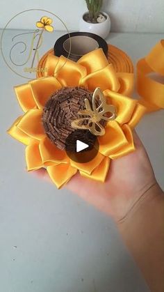 a hand holding a flower made out of ribbon