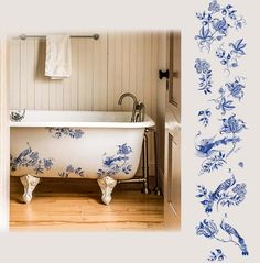 an old bathtub with blue flowers painted on the wall next to a towel rack