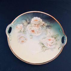 a plate with flowers painted on it sitting on a black table top next to a wall