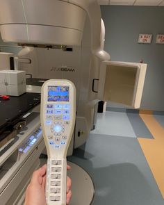 a person holding a remote control in front of a machine