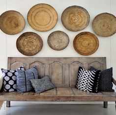 a wooden bench sitting in front of a wall filled with baskets on top of it