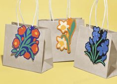 three bags with flowers painted on them are sitting in front of a yellow background,