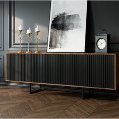 a black and gold sideboard with two candles on it in front of a painting