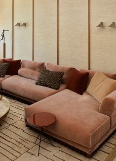 a living room filled with lots of pink couches and pillows on top of a rug