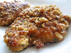 two pieces of fried chicken on a white plate with parmesan and seasoning