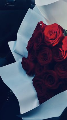 a bouquet of red roses sitting on top of a piece of paper in the back seat of a car