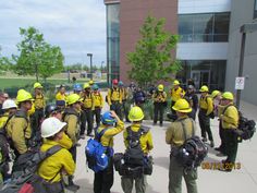 a group of firemen standing around each other in front of a building with backpacks on their backs