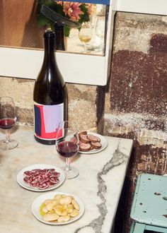 a table topped with plates of food next to a bottle of wine and two glasses