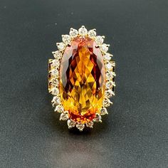 25CT OVAL IMPERIAL TOPAZ & 1.30CTW VS2-SI1 G-H DIAMOND RING - 18K YG - SZ 7.75 *Comes with Original Apprasial from 2000 with an estimated retail replacement value of $21,000 Dimensions: Width: 20.5mm Height: 28.5mm Band Width: 7mm - 10mm Material: 18k Yellow Gold Topaz: 25CT Oval Imperial Topaz # of Diamonds: 26 Diamonds: 1.30CTW VS2-SI1 G-H Round Diamonds Weight: 19g Lovejoy Antiques is a family run business on 5th Avenue South in Naples, Florida, which has been in the same location for twenty-six years. Gold Topaz, Imperial Topaz, 5th Avenue, Naples Florida, Gold Band, Round Diamonds, Topaz, Diamond Ring, Jewelry Rings