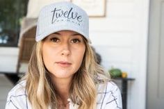 a woman wearing a hat with the word true love on it sitting in front of a house