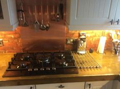 a stove top oven sitting inside of a kitchen next to a counter with pots and pans on it