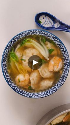 a bowl of soup with shrimp and broccoli in it next to a spoon