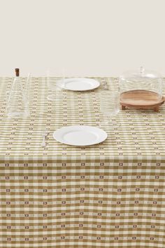 a table topped with plates and glasses on top of a checkered cloth covered table