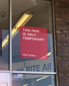 a red sign that is on the side of a window saying, this pain is only temporary keep going