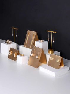 gold jewelry is displayed on white pedestals in front of a black wall and floor