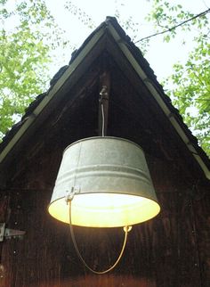 a lamp hanging from the side of a wooden building with trees in the back ground