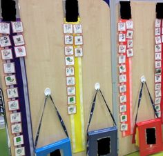 four different colored dog houses hanging on the wall in front of a bulletin board with pictures attached to them