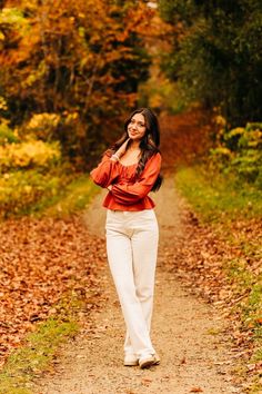 a woman is walking down a path in the woods with her hands on her hips