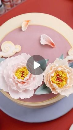 a cake decorated with flowers and seashells on a red tableclothed surface